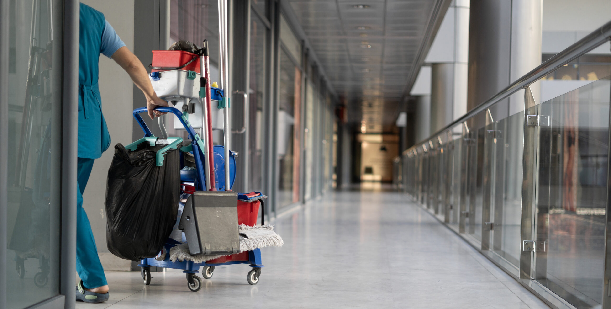 Business van rental solutions for integrated FM - image shows office cleaner dragging trolley through modern office corridor